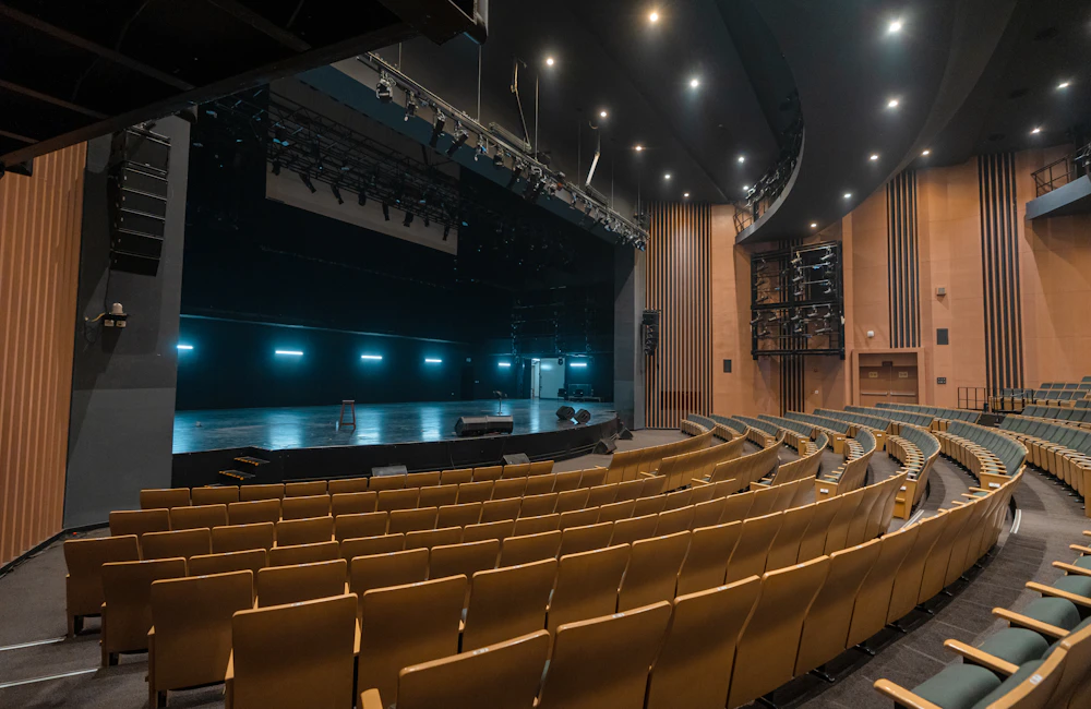 An empty theatre with a stage and rows of audience seating
